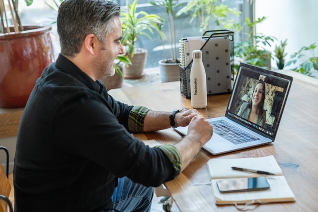 A middle aged man in a virtual meeting with a smiling woman