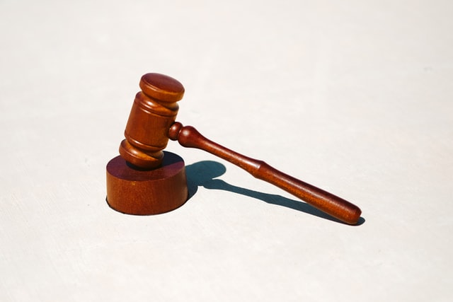 A brown gavel and a block used in a court of law against a white background