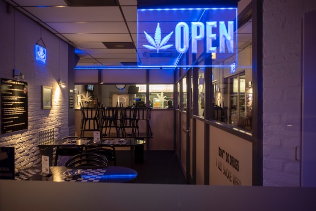 A blue neon open sign inside a cannabis coffee shop