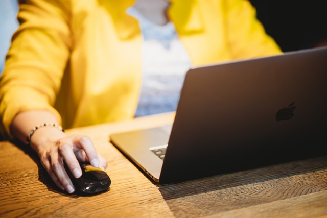 woman in yellow blazer using a mouse and laptop