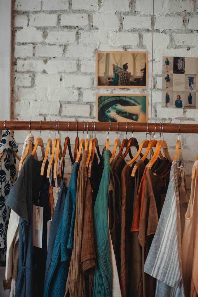 rack of clothes against a brick wall