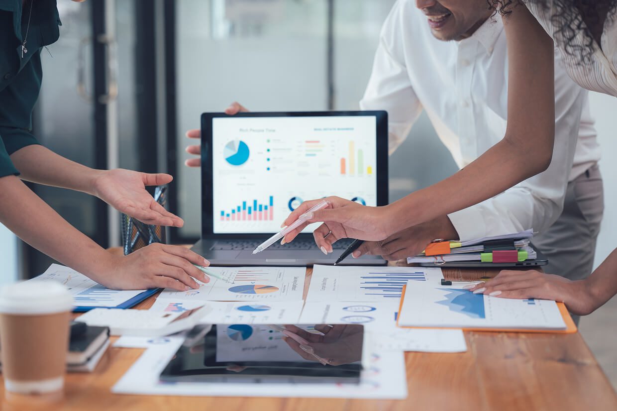 people in front of a laptop with charts on reporting