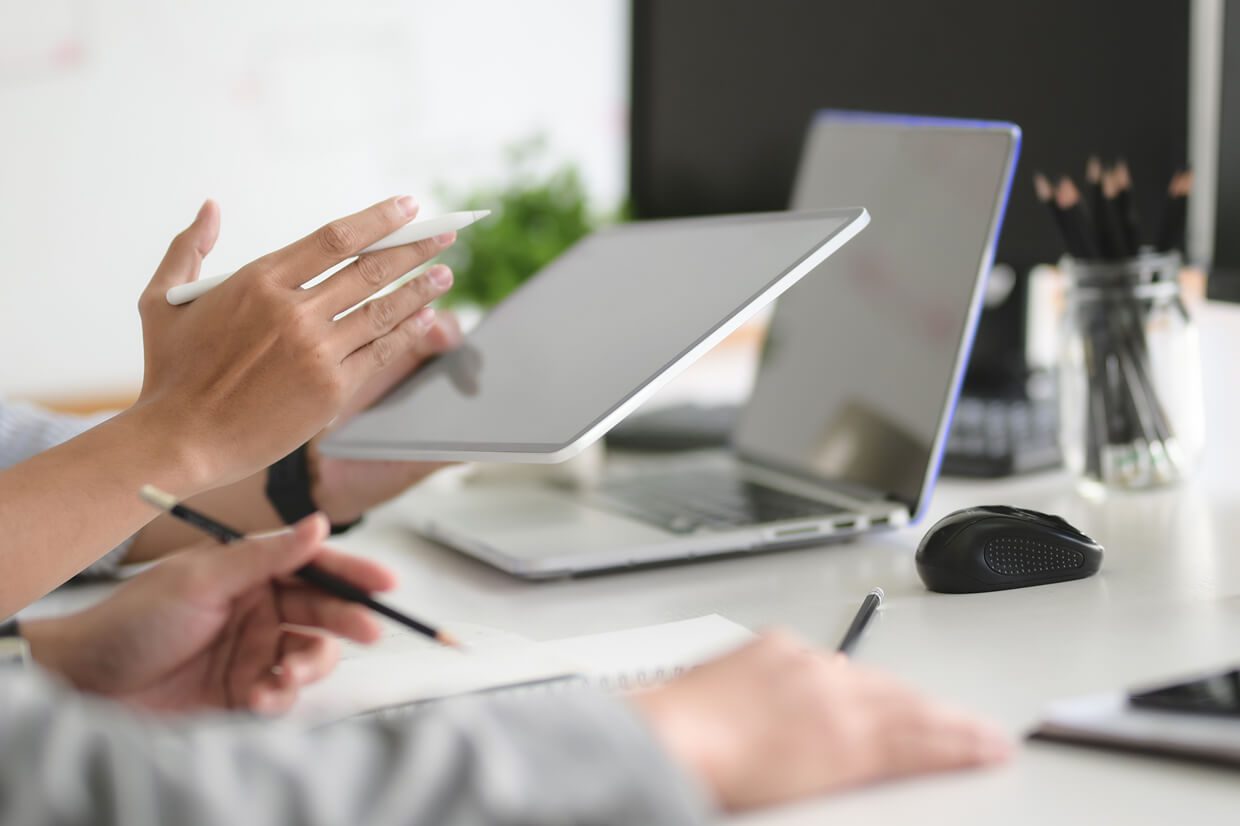 close up on hands holding a tablet and laptop on a table