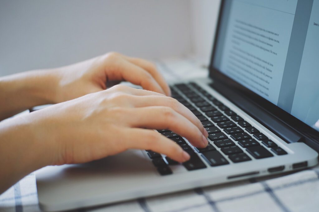 Hands typing on a computer with the screen showing 