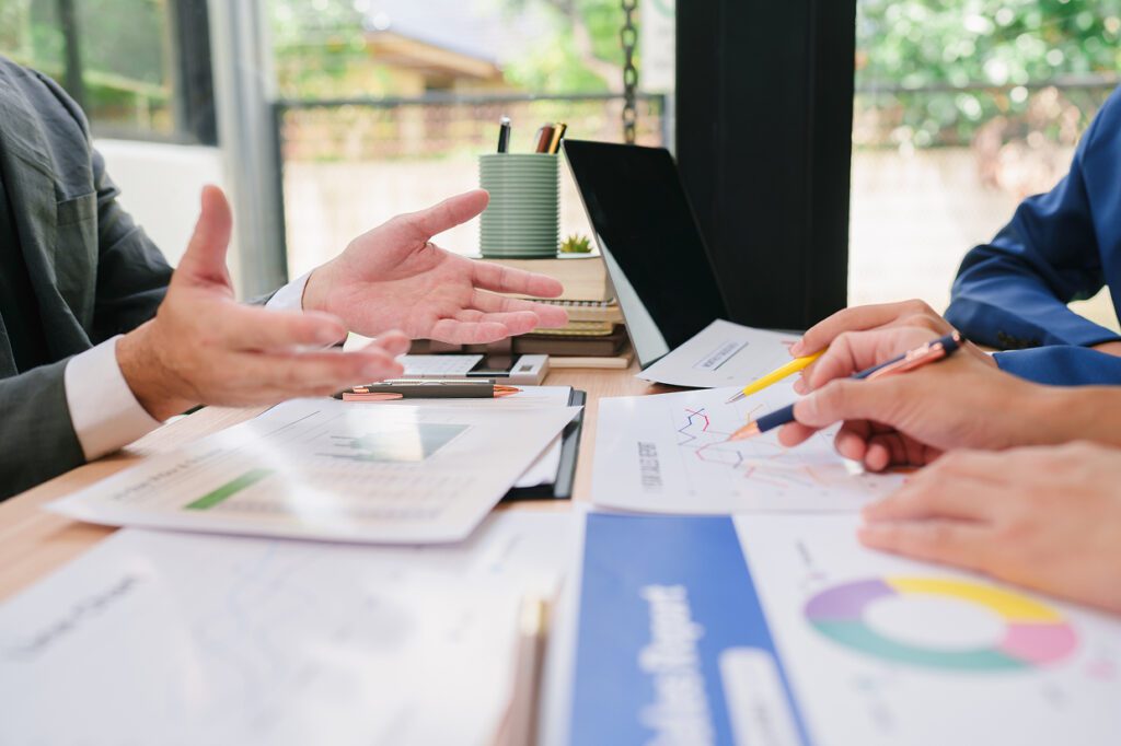 Individuals around a table with pencils and papers