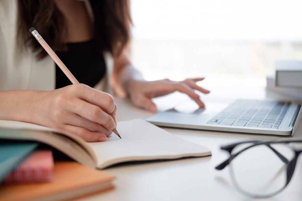 Female writing at a desk with a keyboard