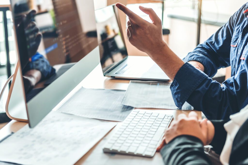 Hand pointing to screen with keyboard and paper on desk