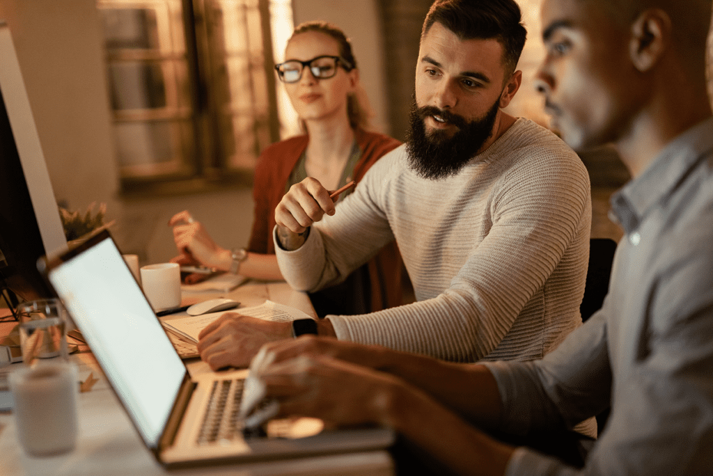 3 individuals seated and looking at a monitor