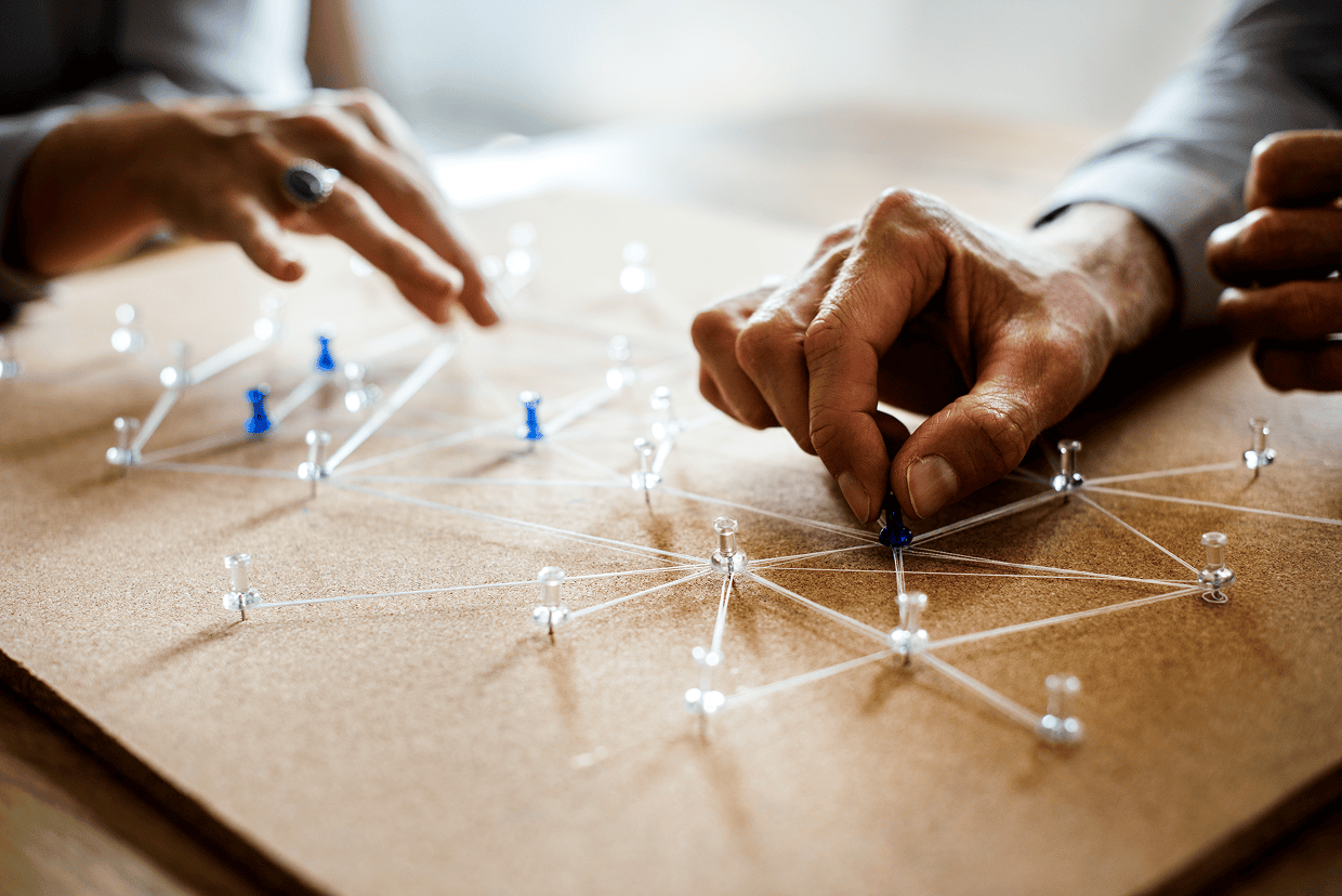 2 individuals arranging multiple thumb tacks on a table